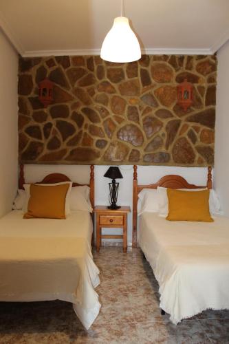 2 camas en una habitación con una pared de piedra en Casa La Azotea de Cazorla en Cazorla