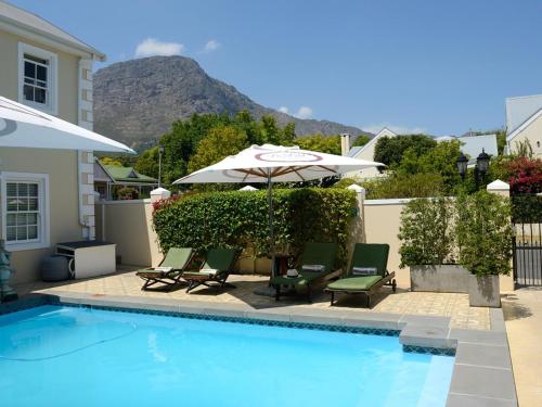 a swimming pool with two chairs and an umbrella and an umbrella at Le Petit Paris in Franschhoek