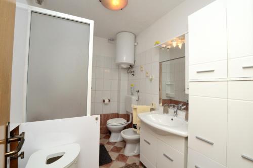 a white bathroom with a toilet and a sink at App Lori in Rabac