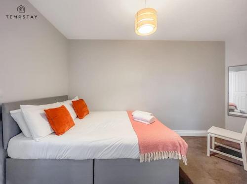 - une chambre avec un lit doté d'oreillers orange et blancs dans l'établissement COSY HOME IN CENTRAL WINDSOR & FREE PARKING, à Windsor