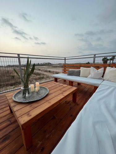 una terraza de madera con un banco y una mesa en סוויטה על שביל הים en Atlit