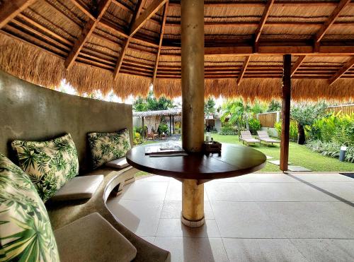 a patio with a table and chairs under a straw umbrella at Halamanan Residences in Panglao