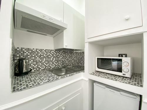 a white kitchen with a microwave and a sink at Locanda Parlamento in Rome