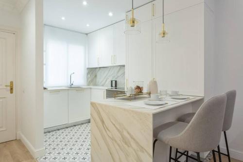a kitchen with white cabinets and a counter with chairs at Exclusiva vivienda en la Calle Jorge Juan in Madrid