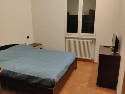 um quarto com uma cama, uma televisão e uma janela em Montenero House em Bolonha