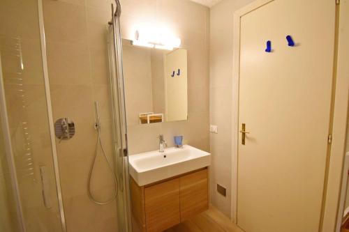 een badkamer met een wastafel en een douche met een spiegel bij Spinale del Sogno in Madonna di Campiglio