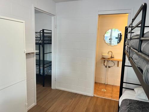 a bedroom with a bunk bed and a hallway with a mirror at CALI Backpackers in Caloundra