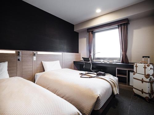 a hotel room with two beds and a window at Mitsui Garden Hotel Okayama in Okayama
