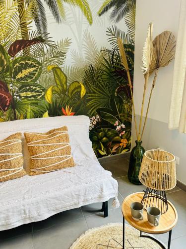 a living room with a white couch and a tropical mural at Studio Bohème hypercentre in Amiens