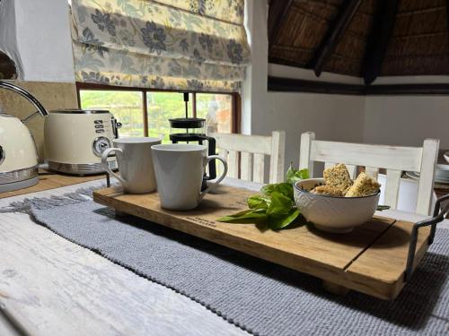 a wooden tray with cups and a bowl of food on a table at Prospect Farm Cottages in George