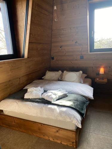 Una cama en una cabaña de madera con dos toallas. en Le Manoir de l'Oselière & Spa, en Les Hauts-Geneveys