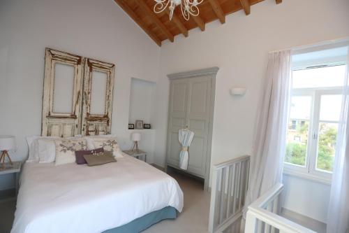 a bedroom with a white bed and a window at 1901 Hermoupolis in Ermoupoli