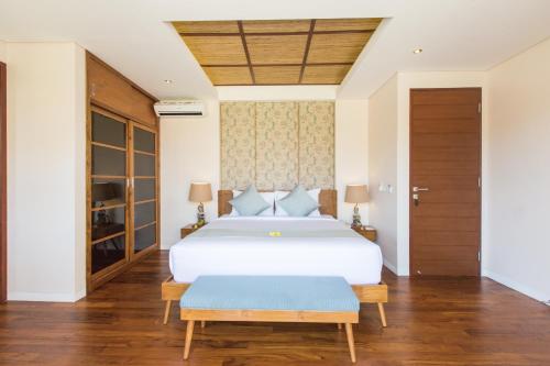 a bedroom with a large white bed with blue pillows at Beautiful Bali Villas in Legian