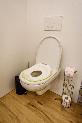 a white toilet in a bathroom with a wooden floor at Dom pri jazere, Bešeňová in Bešeňová