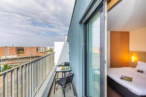 Zimmer mit einem Balkon, einem Bett und einem Schreibtisch. in der Unterkunft ibis Basel Bahnhof in Basel