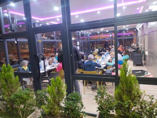 un grupo de personas sentadas en mesas en un restaurante en Hôtel Imilchil en Midelt