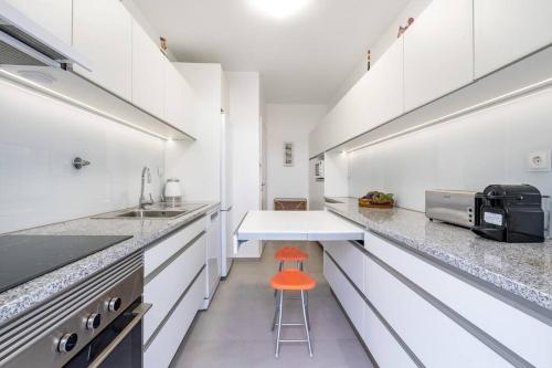 a kitchen with white cabinets and a orange stool at VIVA Casa do Galo in Porto