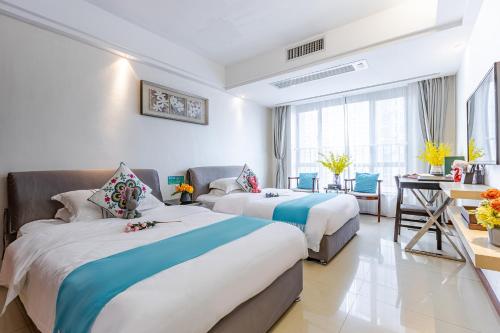 広州市にあるWAIFIDEN service Apartment Min Jian Fianance Branchのベッド2台とデスクが備わるホテルルームです。