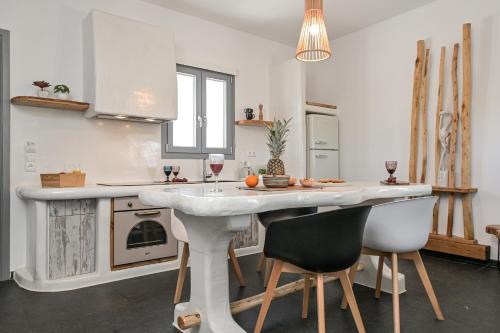 a kitchen with a white counter and a table with chairs at White Cocoon Exclusive villas in Naxos Chora