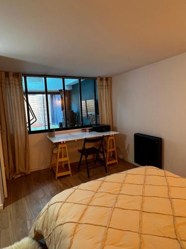 Schlafzimmer mit einem Bett, einem Schreibtisch und einem Fenster in der Unterkunft L’Usine in Concarneau