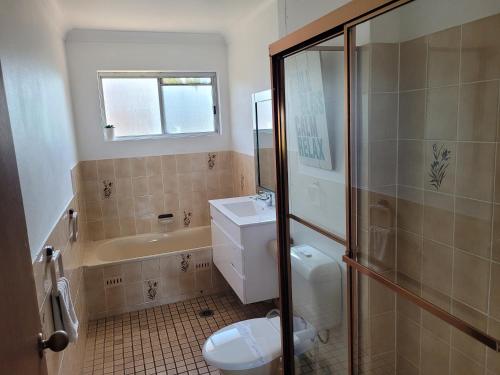 a bathroom with a toilet and a sink and a shower at Reef Resort Apartments in Mona Vale