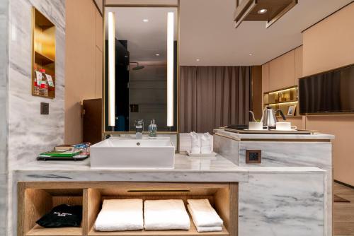 a bathroom with a sink and a counter with towels at Echarm Plus Hotel - Foshan Smart New City Zhangcha Metro Station Branch in Foshan