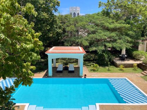 a blue swimming pool with a gazebo in a yard at Hilda's Homestay in Diani Beach