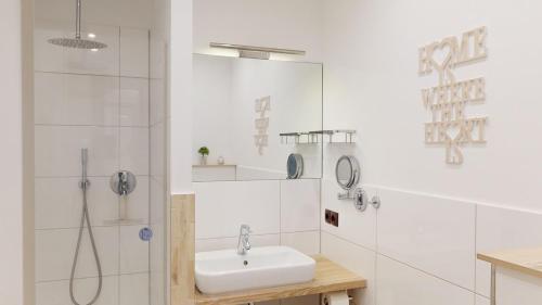 ein weißes Bad mit einem Waschbecken und einer Dusche in der Unterkunft NeuKlosterhof App. 24 in Pelzerhaken