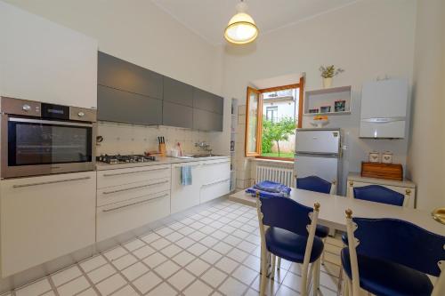 a kitchen with white cabinets and a table with blue chairs at Orsini: tre camere da letto, 2 bagni in Luco dei Marsi