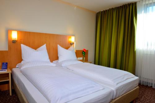 a large bed with white pillows in a bedroom at PLAZA INN Leonberg in Leonberg