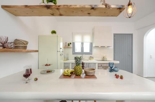 - une cuisine blanche avec une grande île blanche agrémentée de fruits dans l'établissement White Cocoon Exclusive villas, à Naxos Chora