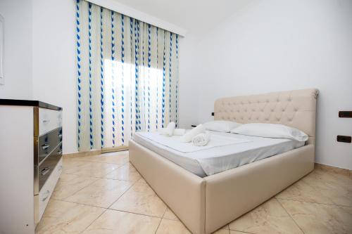 a white bedroom with a large bed and a window at Noa Apartments in Vlorë