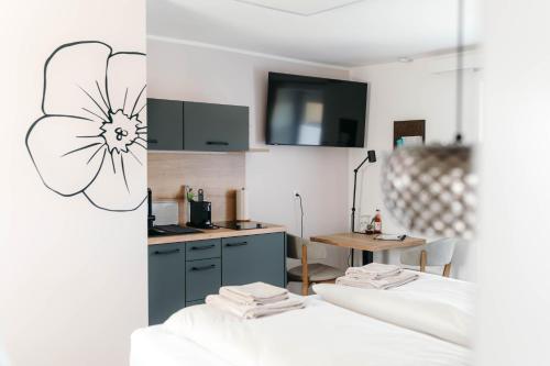 a room with two beds and a kitchen with a flower on the wall at Pension Blumenwiese - Mitten im Thermenland in Burgau