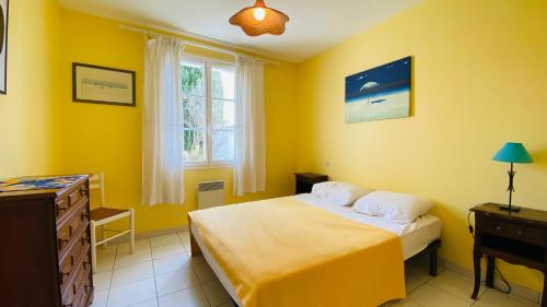 - une chambre jaune avec un lit, une commode et une fenêtre dans l'établissement Villa individuelle de plain pied, à 300m du marché, et 500m de la plage,, au Bois-Plage-en-Ré