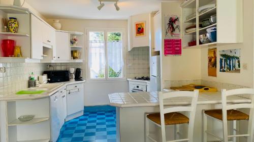 Il comprend une cuisine avec des placards blancs et du carrelage bleu. dans l'établissement Villa individuelle de plain pied, à 300m du marché, et 500m de la plage,, au Bois-Plage-en-Ré