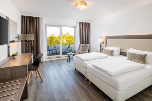 a hotel room with two beds and a desk at Hotel Newton Ludwigshafen in Ludwigshafen am Rhein