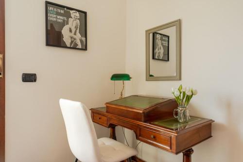 a desk with a white chair next to a desk with flowers at Attico vicino Milano, MXP, Rho Fiera in Busto Arsizio