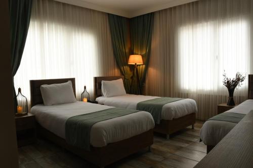 a hotel room with two beds and two windows at Cibali Hotel Istanbul in Istanbul