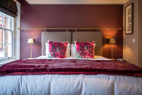 a bedroom with a large bed with red pillows at At Home Apartments in Shrewsbury