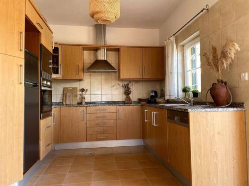 a large kitchen with wooden cabinets and a window at Maison Algarve in Mexilhoeira Grande