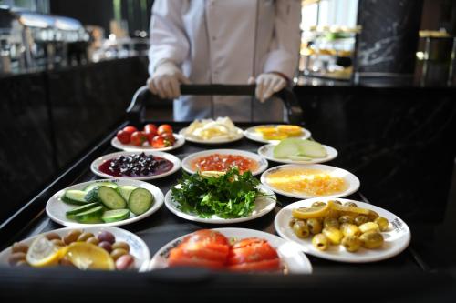 a person standing behind a table with plates of food at Marlen Hotel Bayraklı in Bayrakli