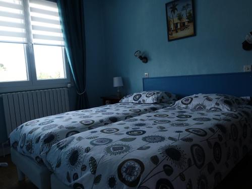 a blue bedroom with a bed with a floral bedspread at LES GRADINES in Bar-sur-Aube