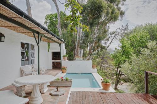 a patio with a pool and a table and a house at Little Willow Brooke in Franschhoek