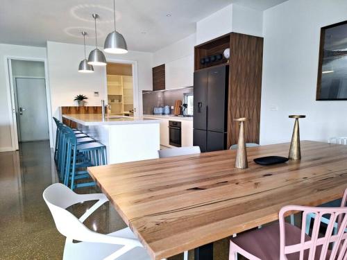 uma grande cozinha com uma mesa de madeira e cadeiras em Hildeton Pool House em Shepparton