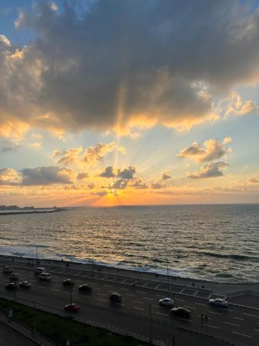 a sunset over the ocean with cars on a highway at Haidar Private bedroom for Men only غرف خاصه للرجال فقط 仅限男性 in Alexandria