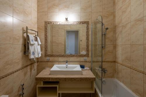 a bathroom with a sink and a shower and a mirror at Metro Hotel Apartments in Odesa