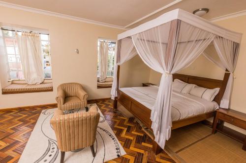 a bedroom with a canopy bed and a chair at The Blixen Resort & Spa in Nairobi