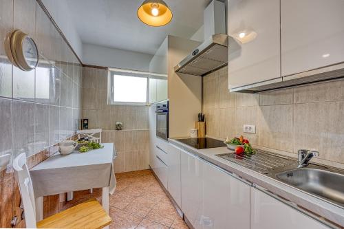 una cocina con armarios blancos y fregadero en Villa Mare, en Rovinj