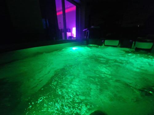 una piscina de agua con luces verdes y moradas en Studio chic jacuzzi, en Portet-sur-Garonne