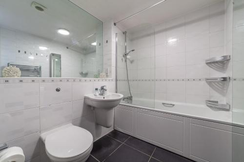 a white bathroom with a toilet and a sink at The Stratford Collection in London